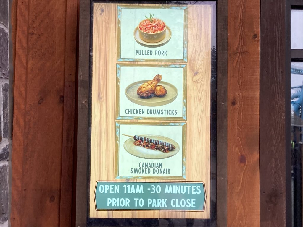 Lazy Bear Lodge's screen next to the entrance. It lists the hours as "Open: 11AM - 30 minutes prior to park close."