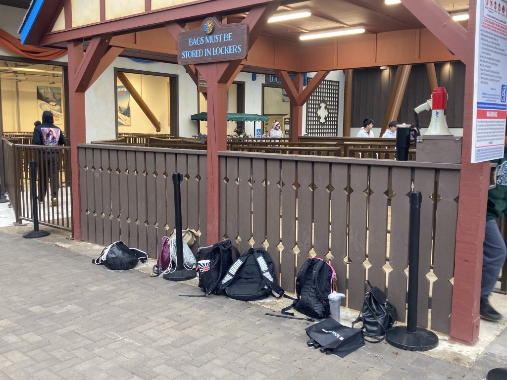 Bags placed directly under a sign stating bags must be placed in a locker.