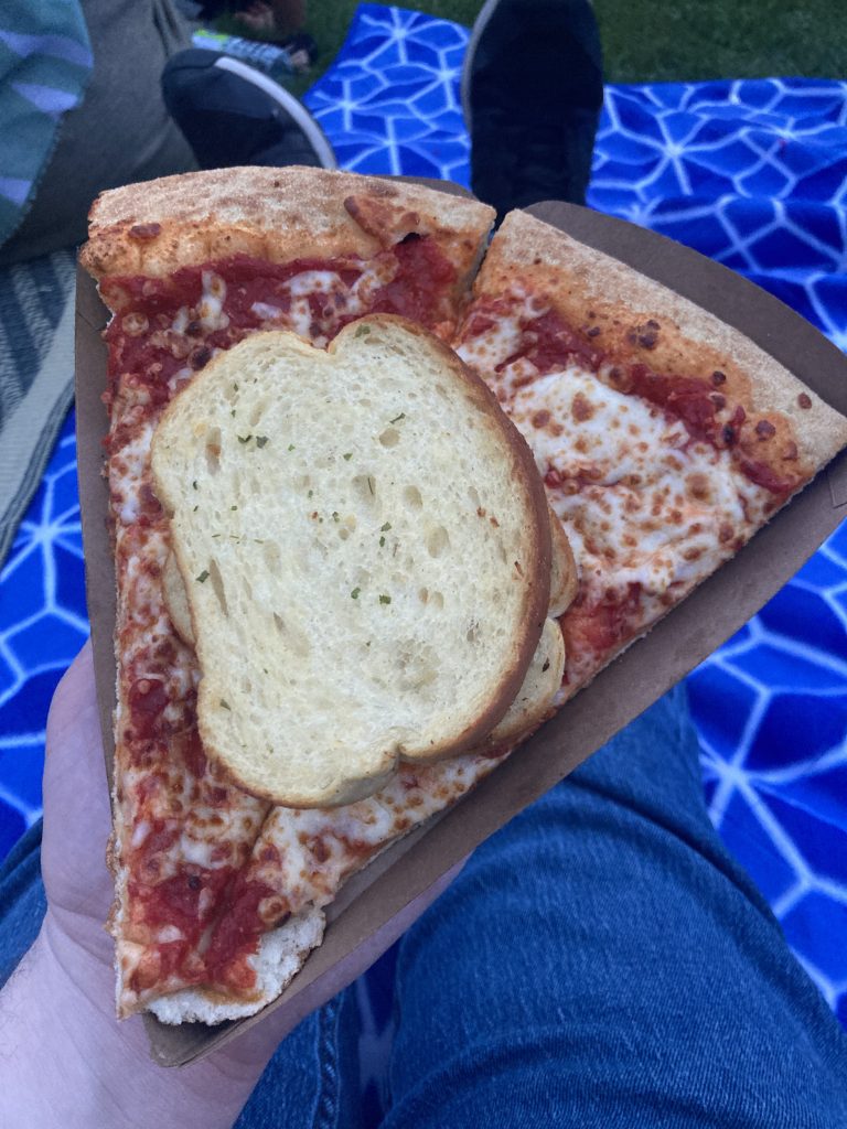 Slice of pizza with two pieces of garlic bread on top.
