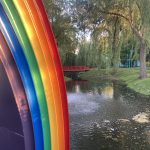 Rainbow bridge with water and trees in the background.