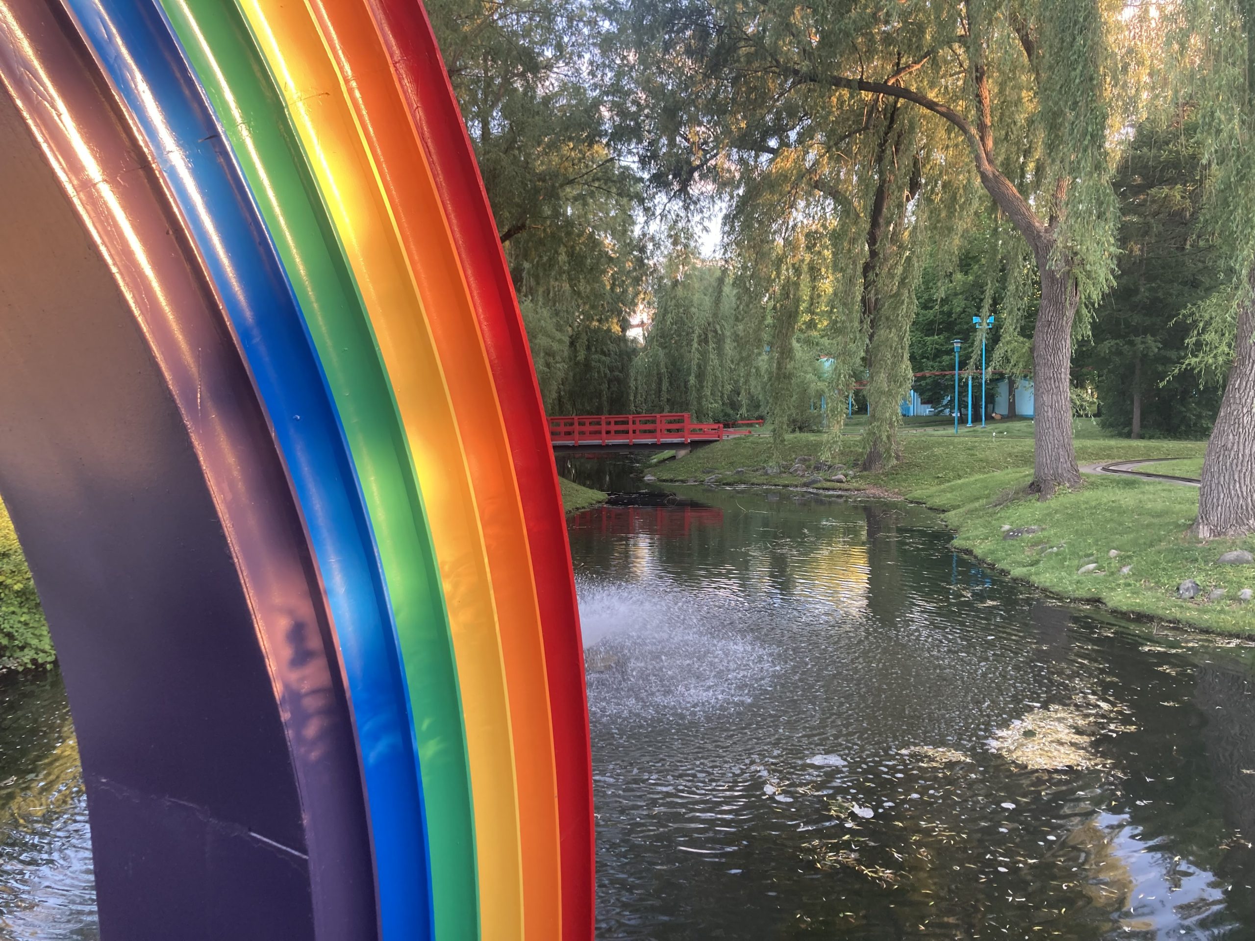 Rainbow bridge with water and trees in the background.