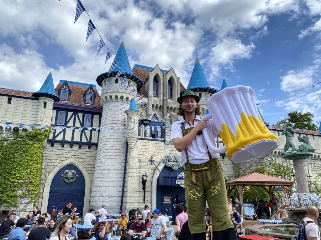 A performer on stilts, holding an inflatable stein.